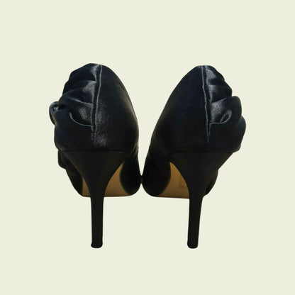 Pair of black high-heeled shoes on a beige background