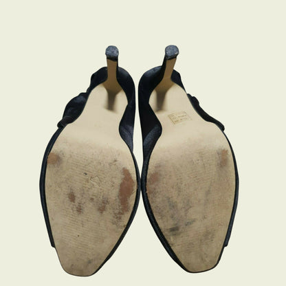 Pair of black shoes with worn soles on a beige background