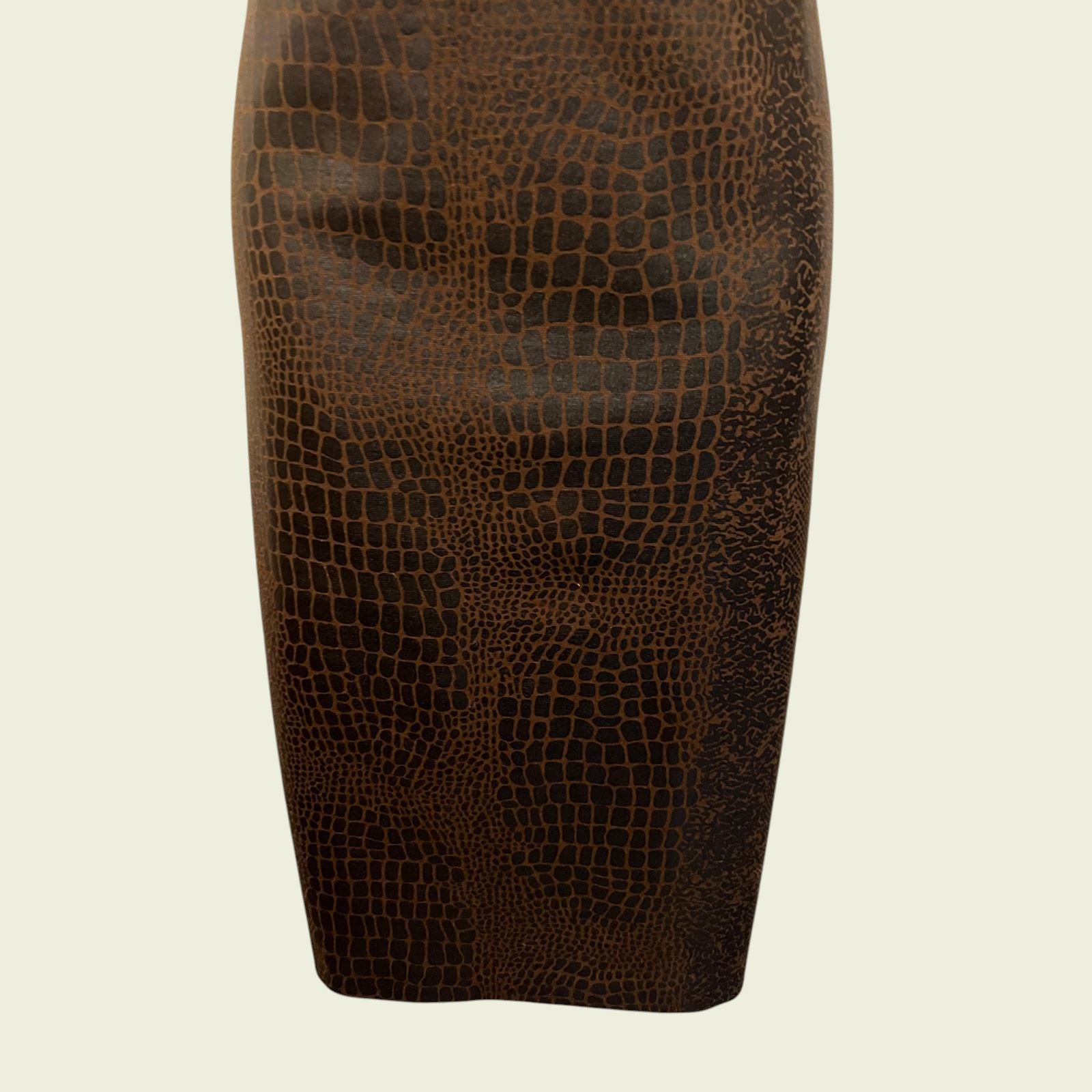Brown leather pencil skirt with crocodile texture on a beige background
