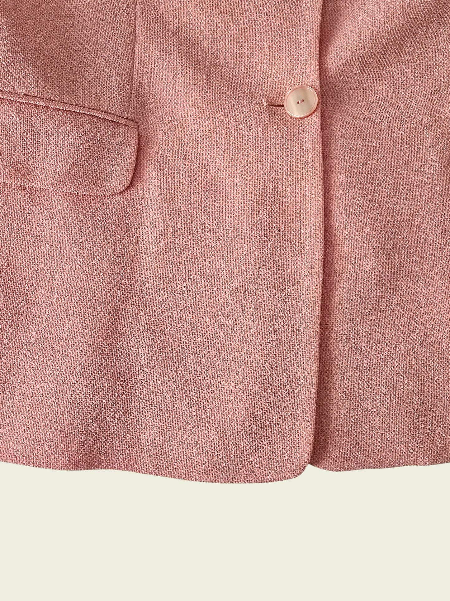 Close-up of a pink fabric with a button on a light green background