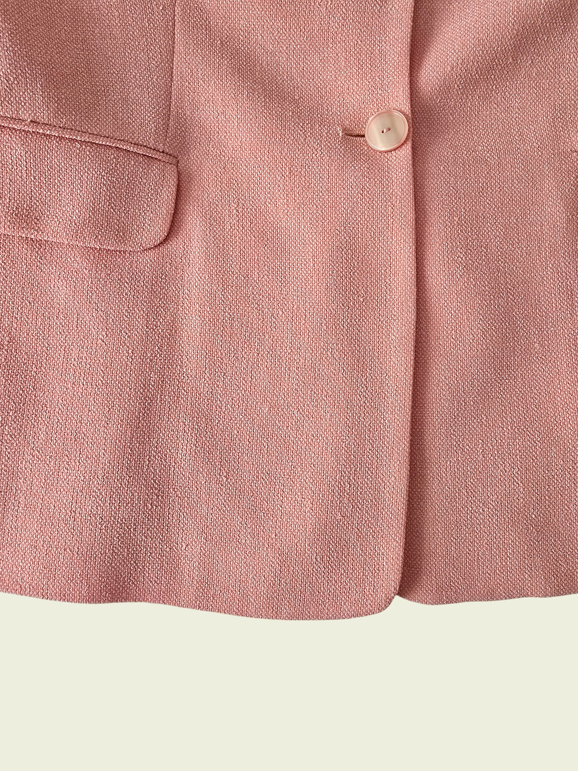Close-up of a pink fabric with a button on a light green background