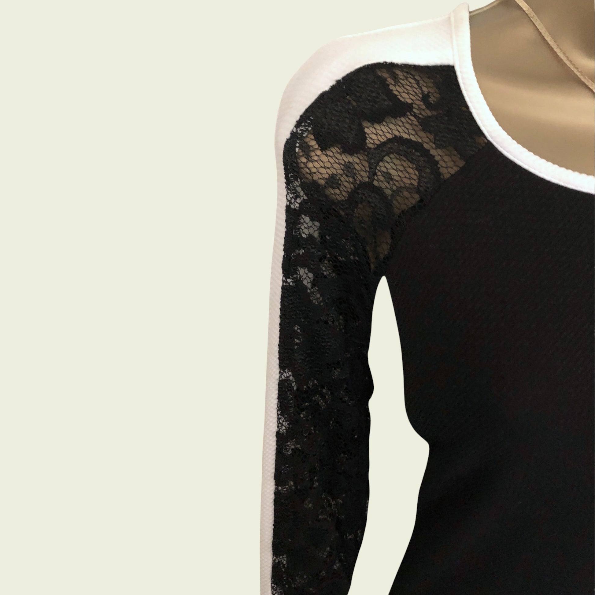 Black long-sleeve dress with lace detailing on a beige background