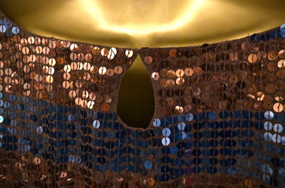Close-up of a sequined fabric with a gold circular object on top