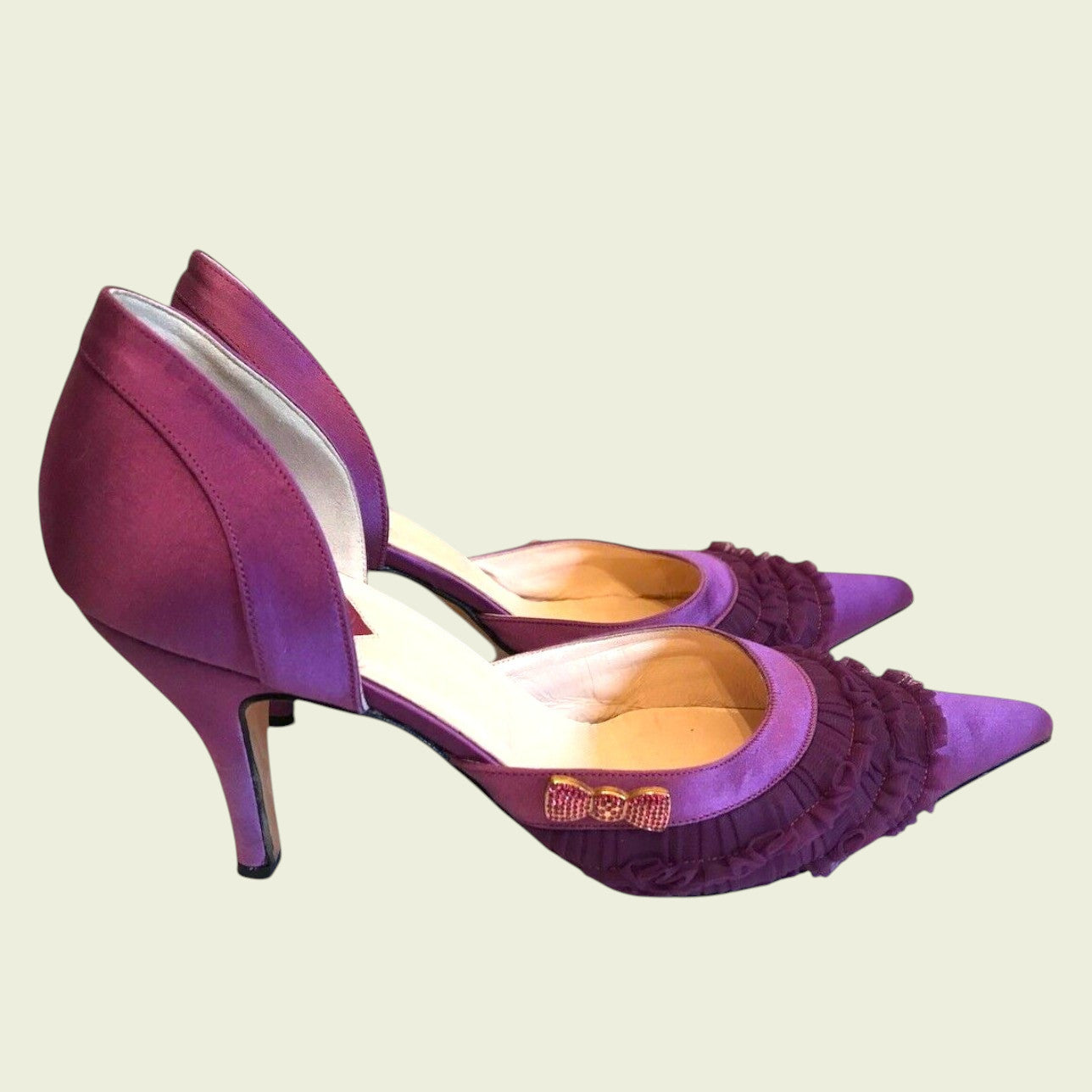Purple high-heeled shoes with ruffled details on a beige background