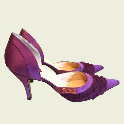 Purple high-heeled shoes with ruffled details on a beige background