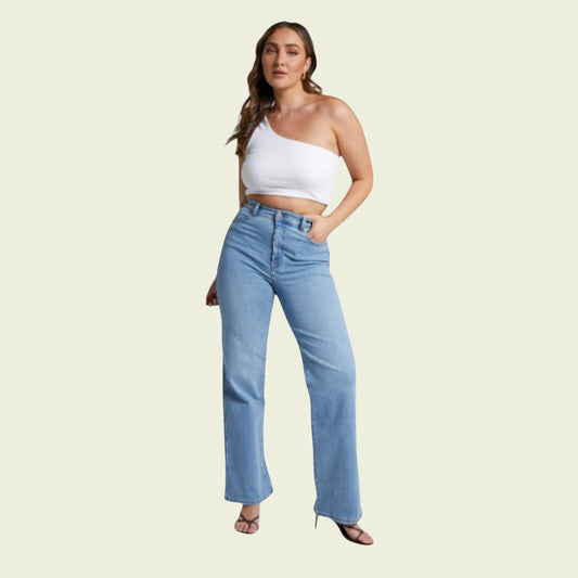 Woman wearing a white one-shoulder top and blue jeans on a beige background
