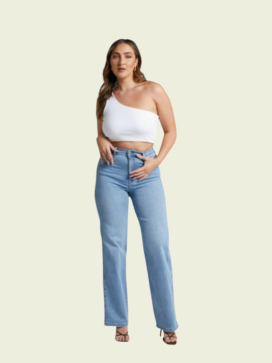 Woman wearing a white one-shoulder top and light blue jeans on a beige background
