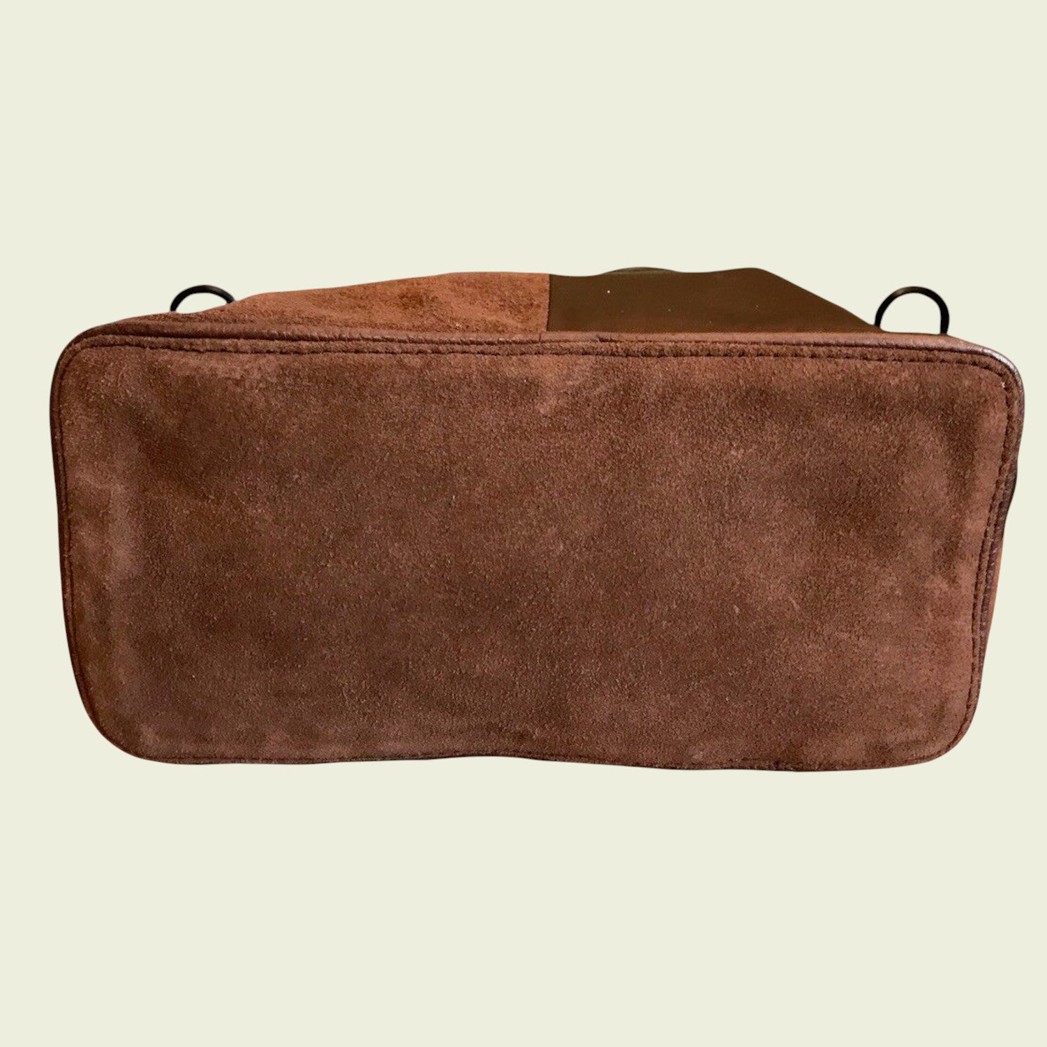 Bottom of brown leather bag on a beige background