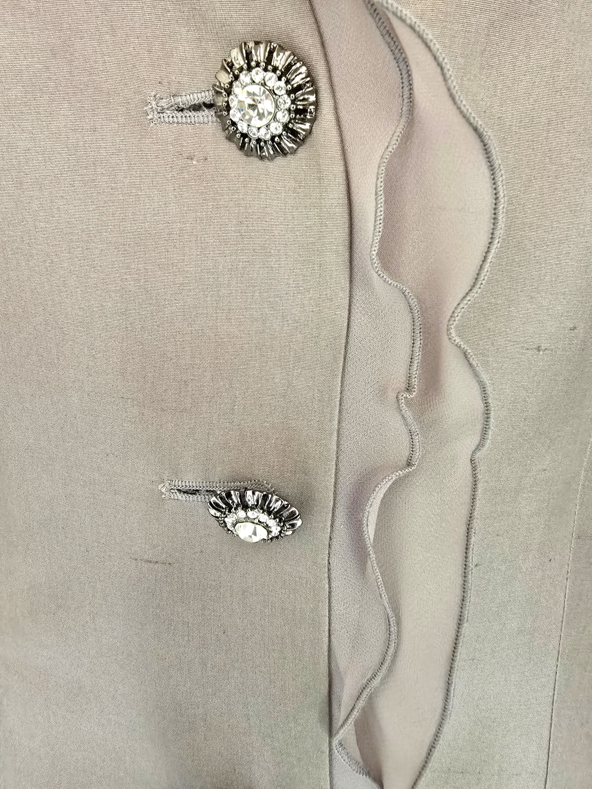 Pair of silver buttons with gemstones on a beige fabric background