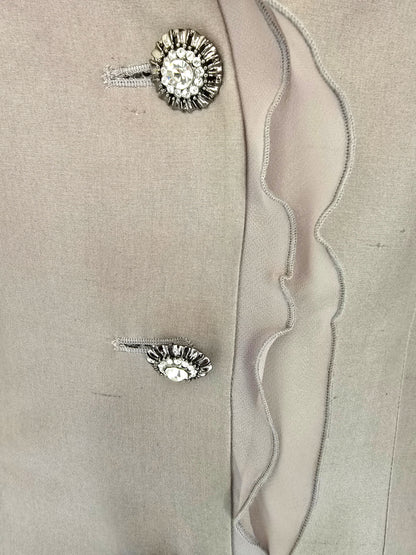 Pair of silver buttons with gemstones on a beige fabric background