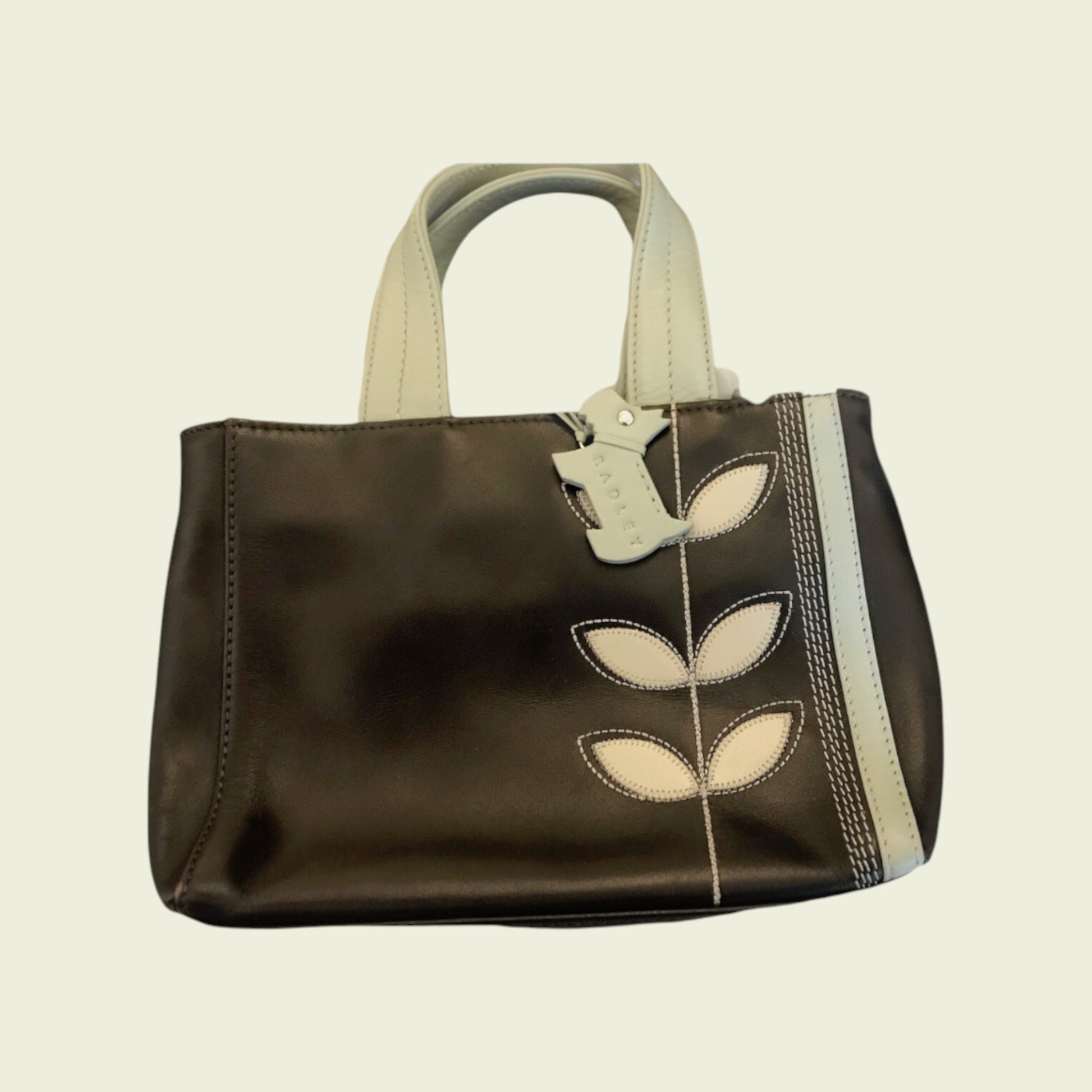 Brown handbag with leaf designs on a beige background