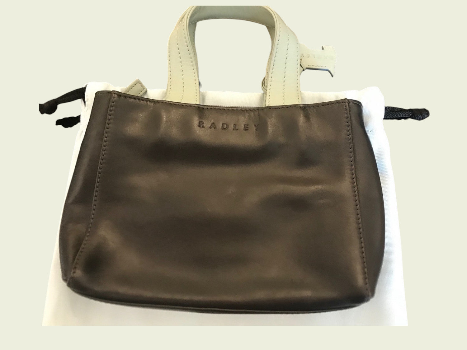Brown handbag with beige handle on a white background