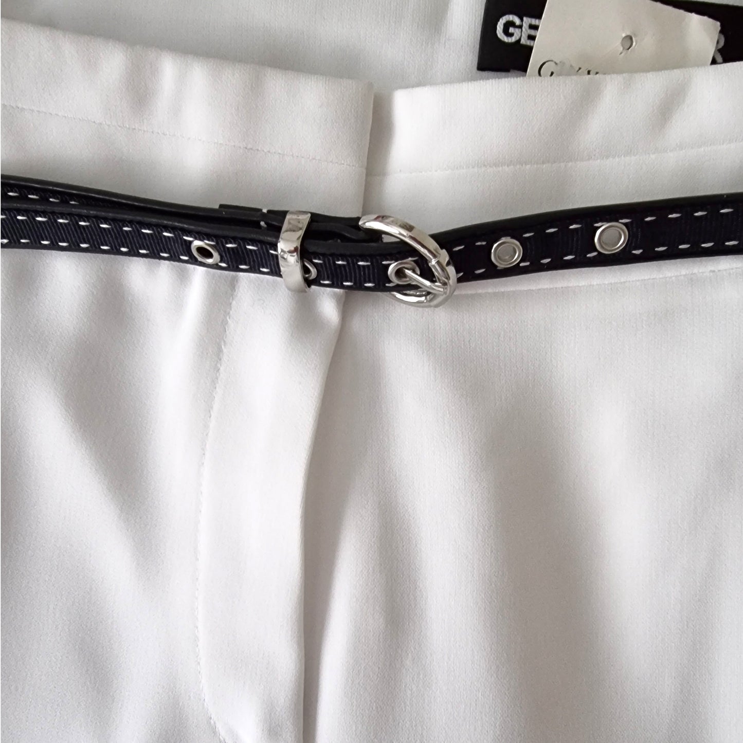 Close-up of a navy belt with silver buckle on a white shirt.