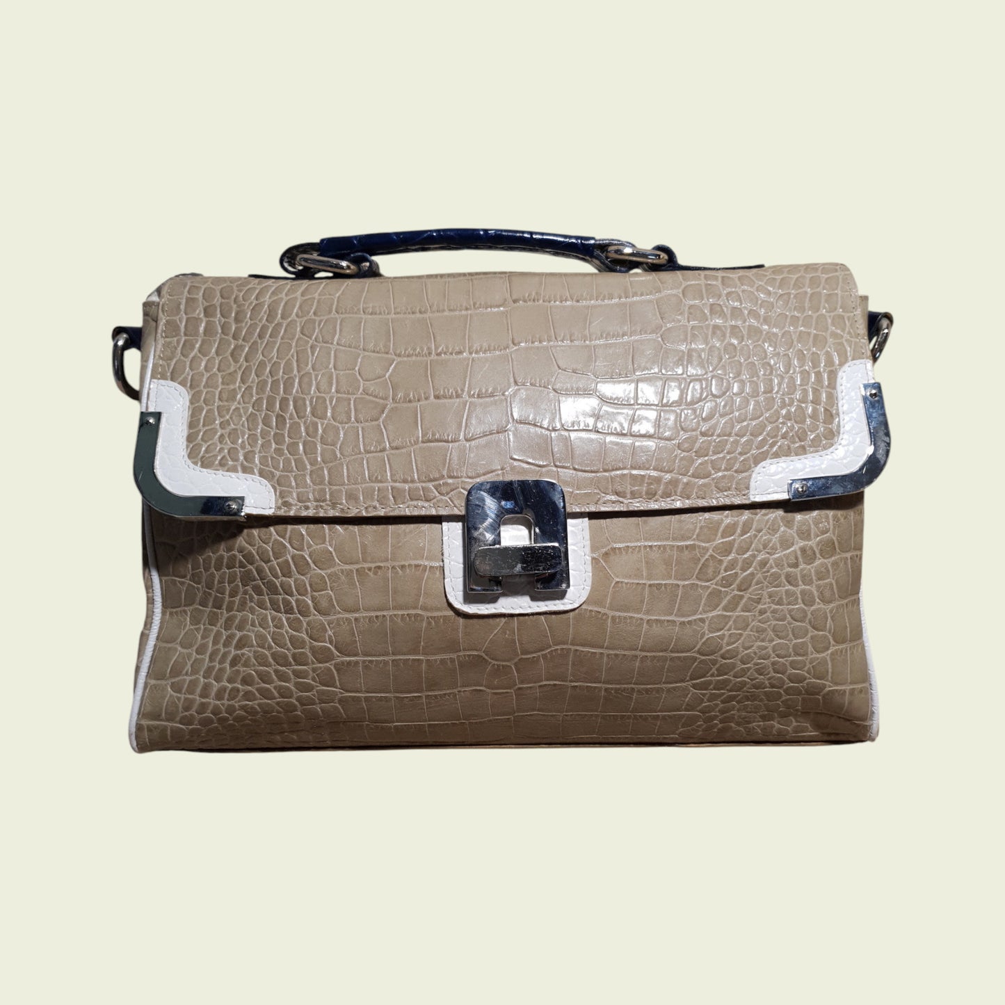 Beige crocodile-patterned handbag with silver accents on a beige background
