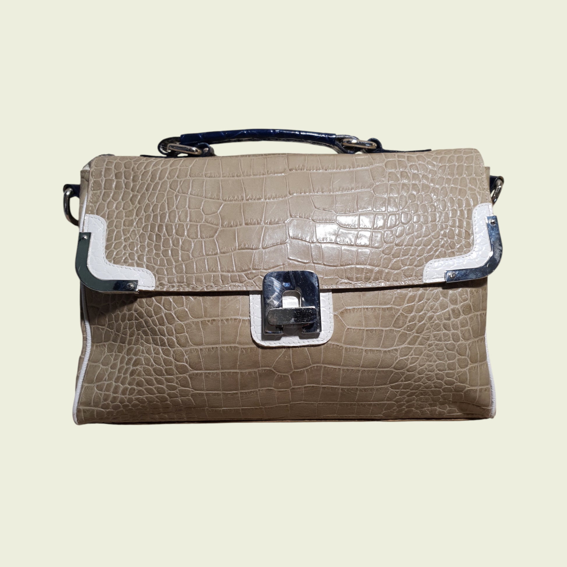 Beige crocodile-patterned handbag with silver accents on a beige background