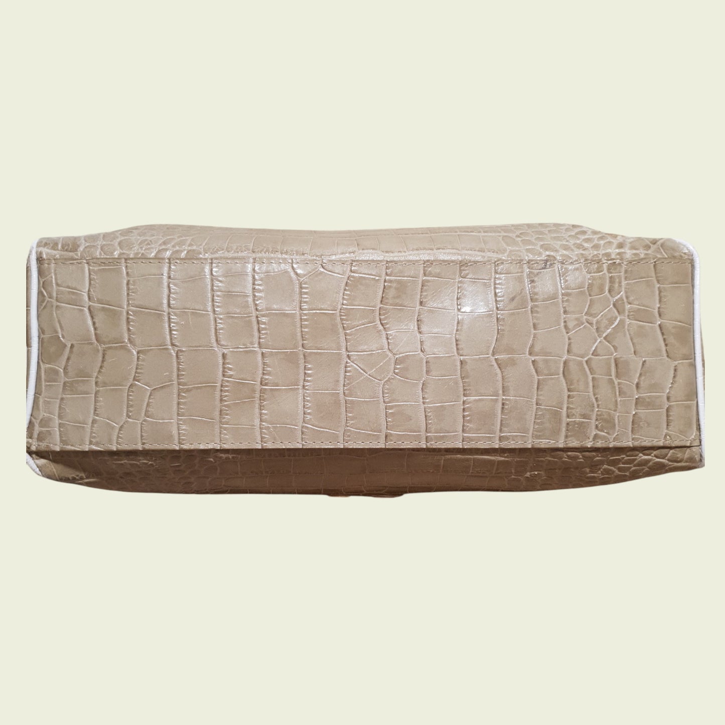 Bottom of bag with crocodile texture on a beige background