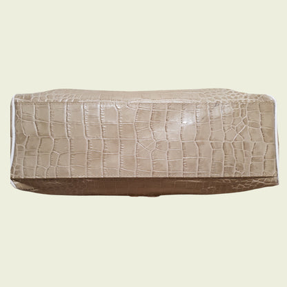 Bottom of bag with crocodile texture on a beige background