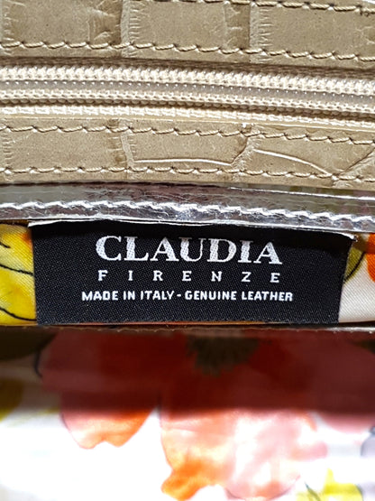 Close-up of a leather wallet with 'Claudia Firenze' label on a floral background