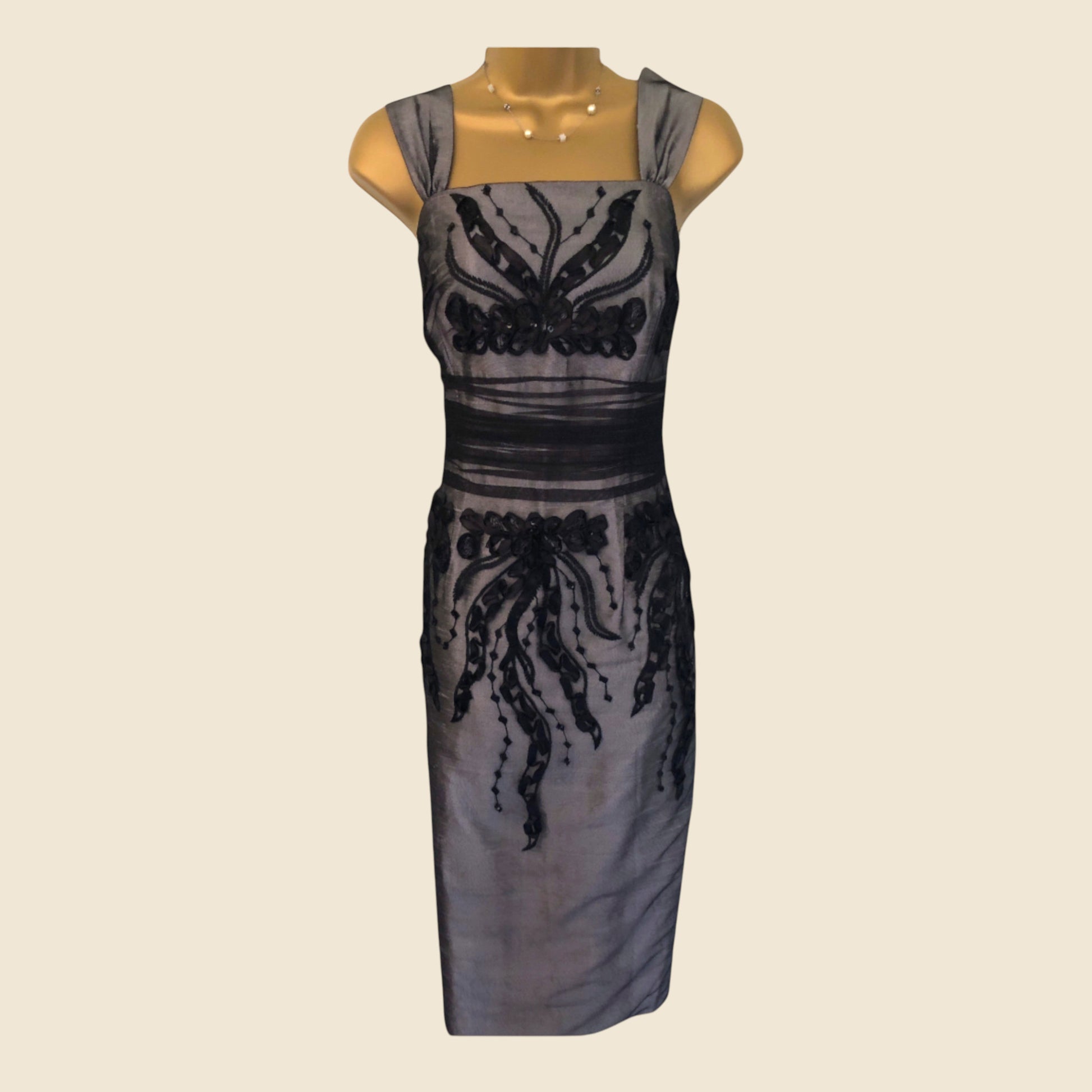 Gray dress with black lace details on a beige background