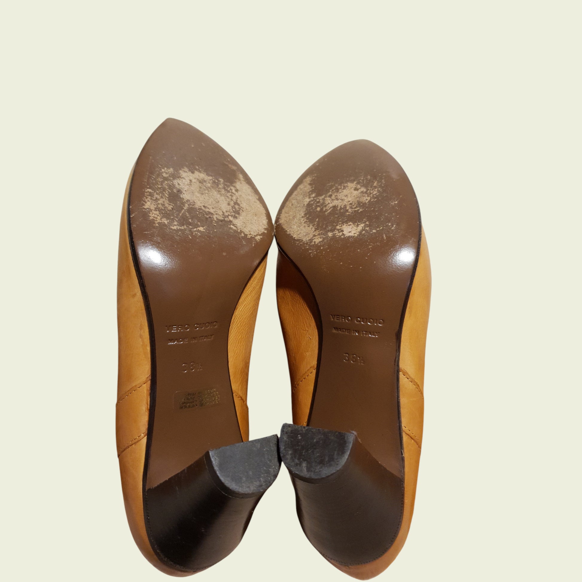 Underside of tan boots on a beige background