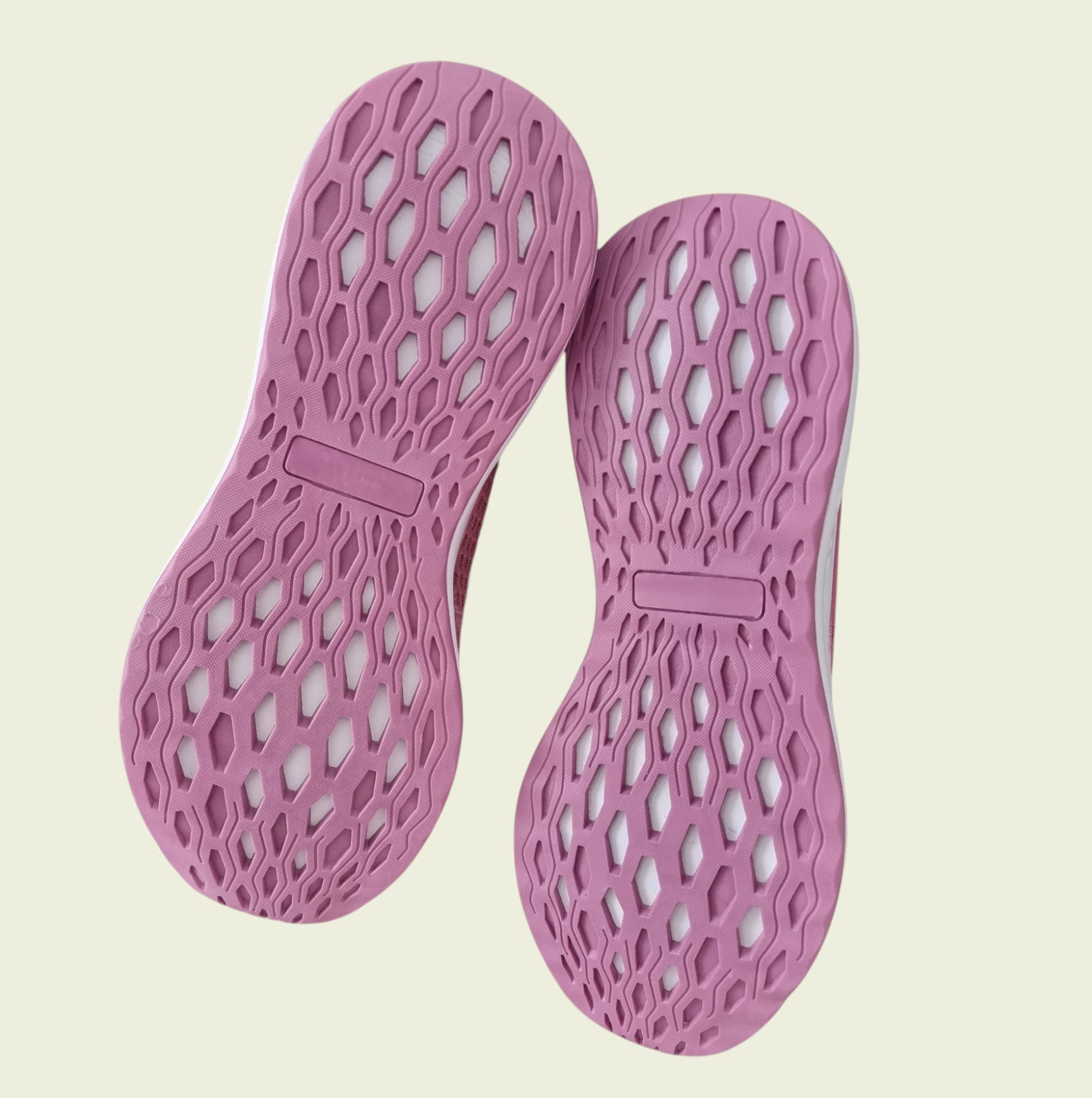 Pink shoe soles with a textured pattern on a beige background
