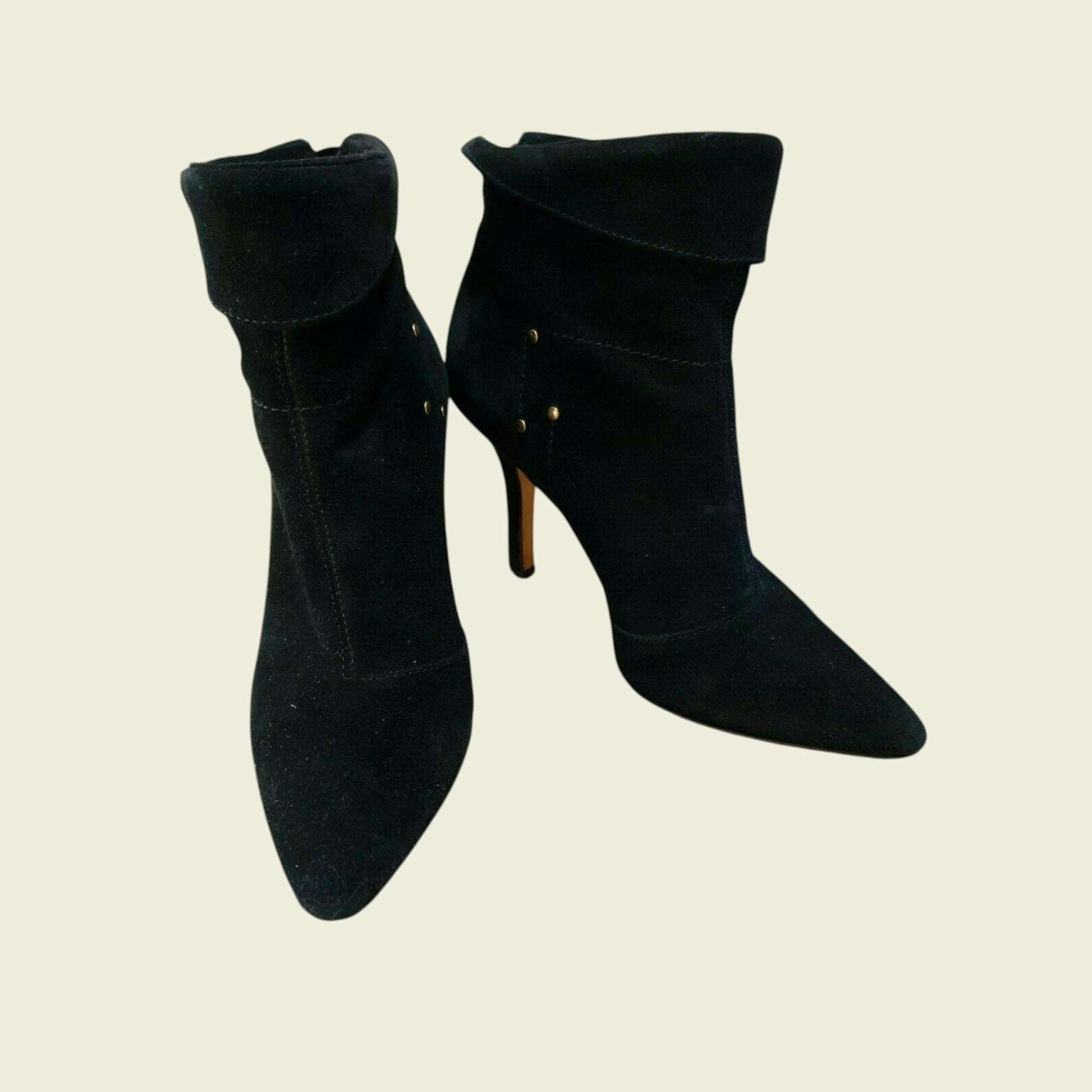 Pair of black high-heeled ankle boots on a beige background