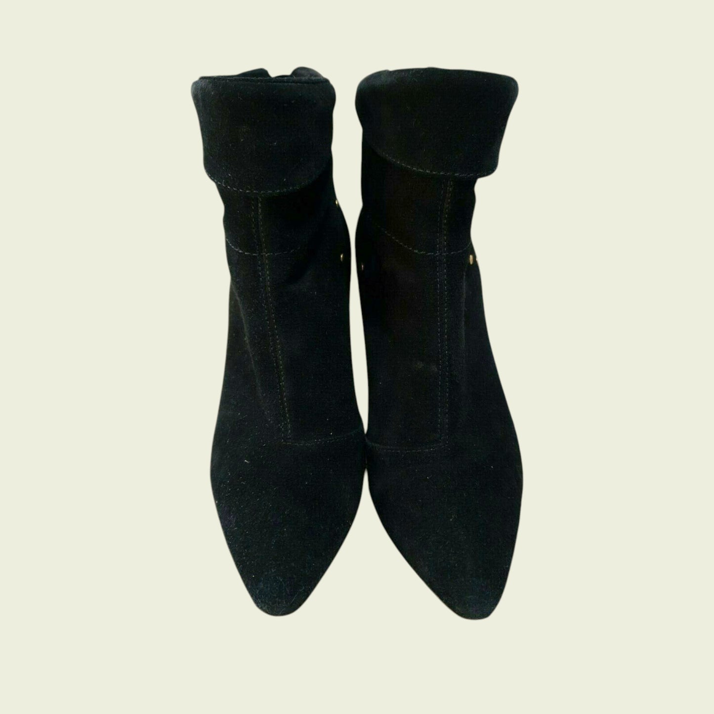Pair of black suede ankle boots on a beige background
