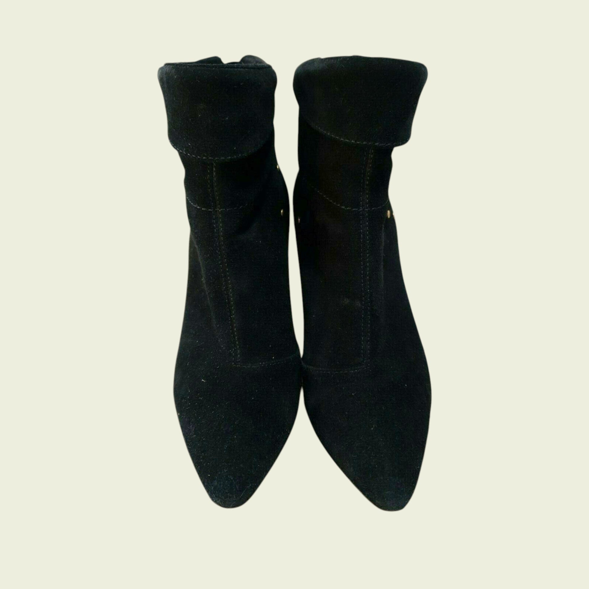 Pair of black suede ankle boots on a beige background