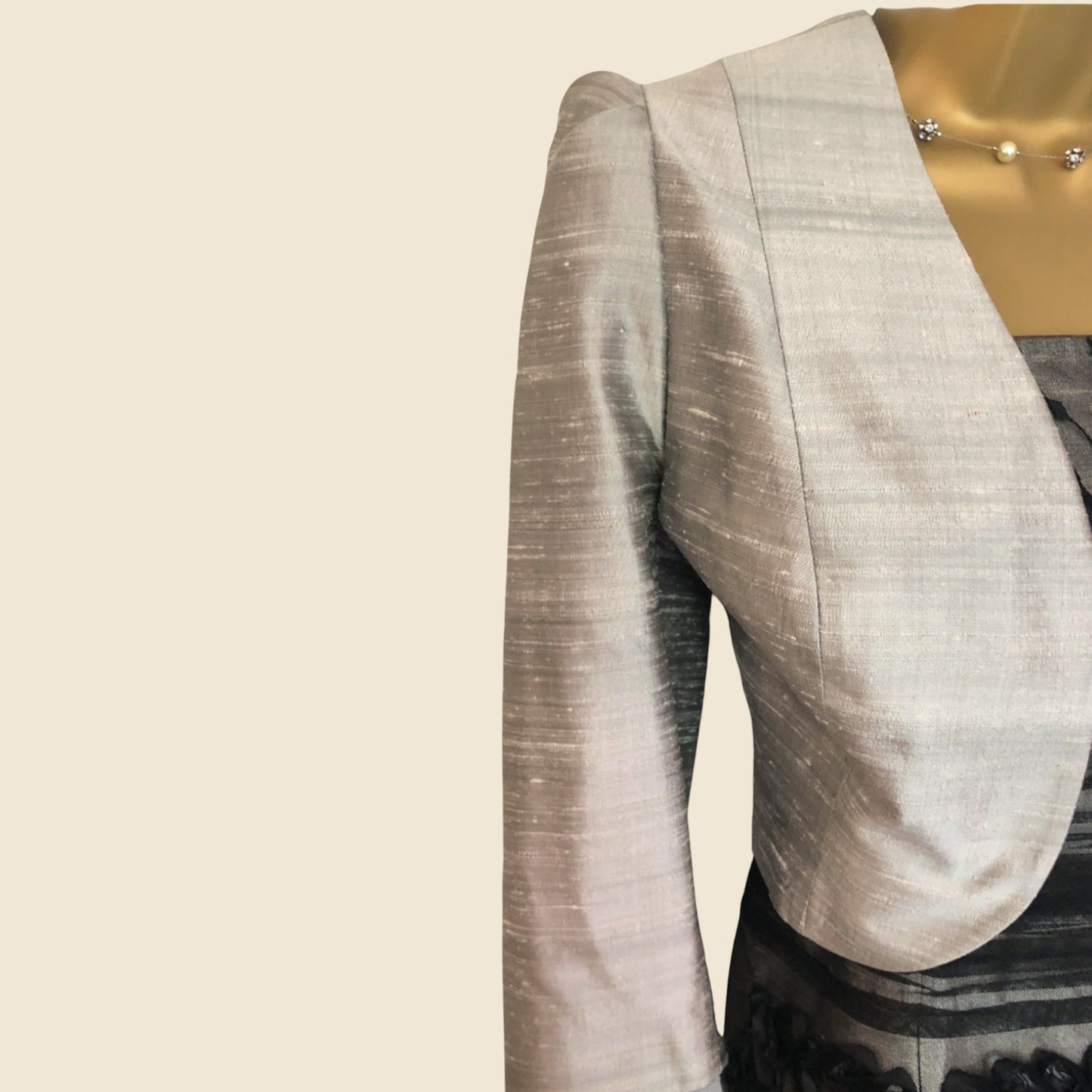 Light gray bollero with a subtle pattern on a beige background