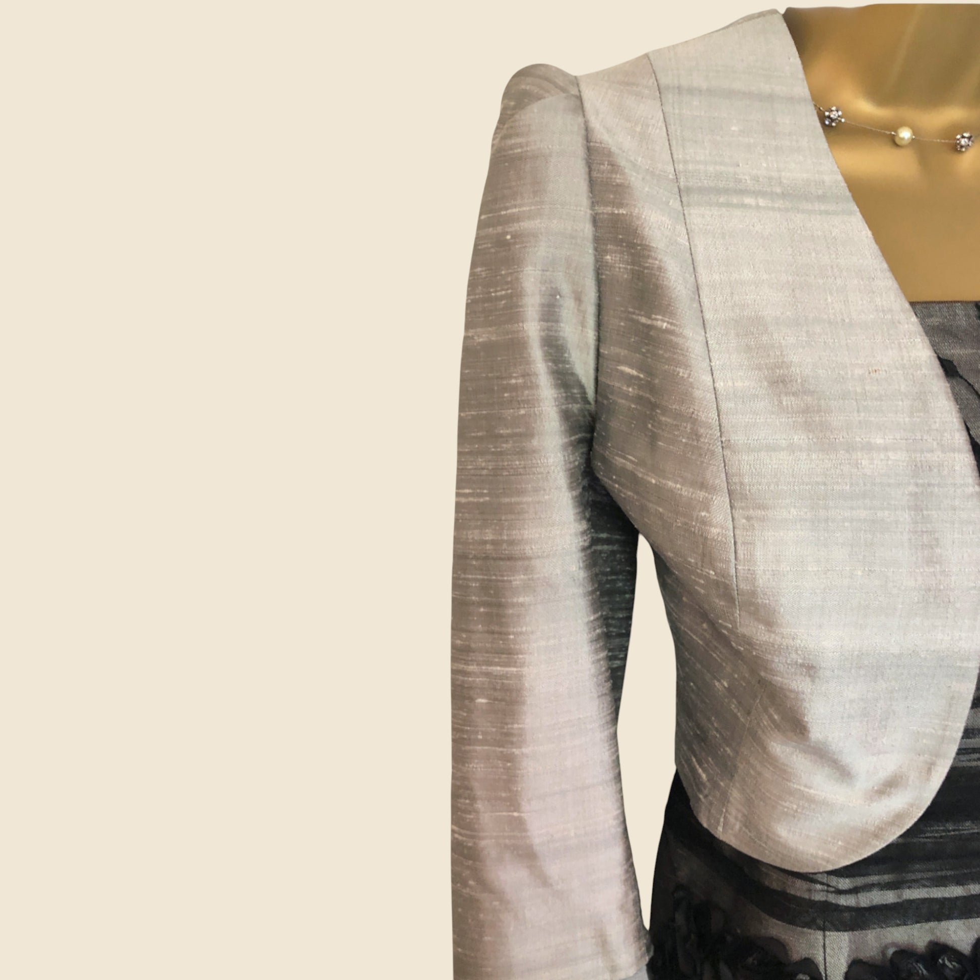 Light gray bollero with a subtle pattern on a beige background