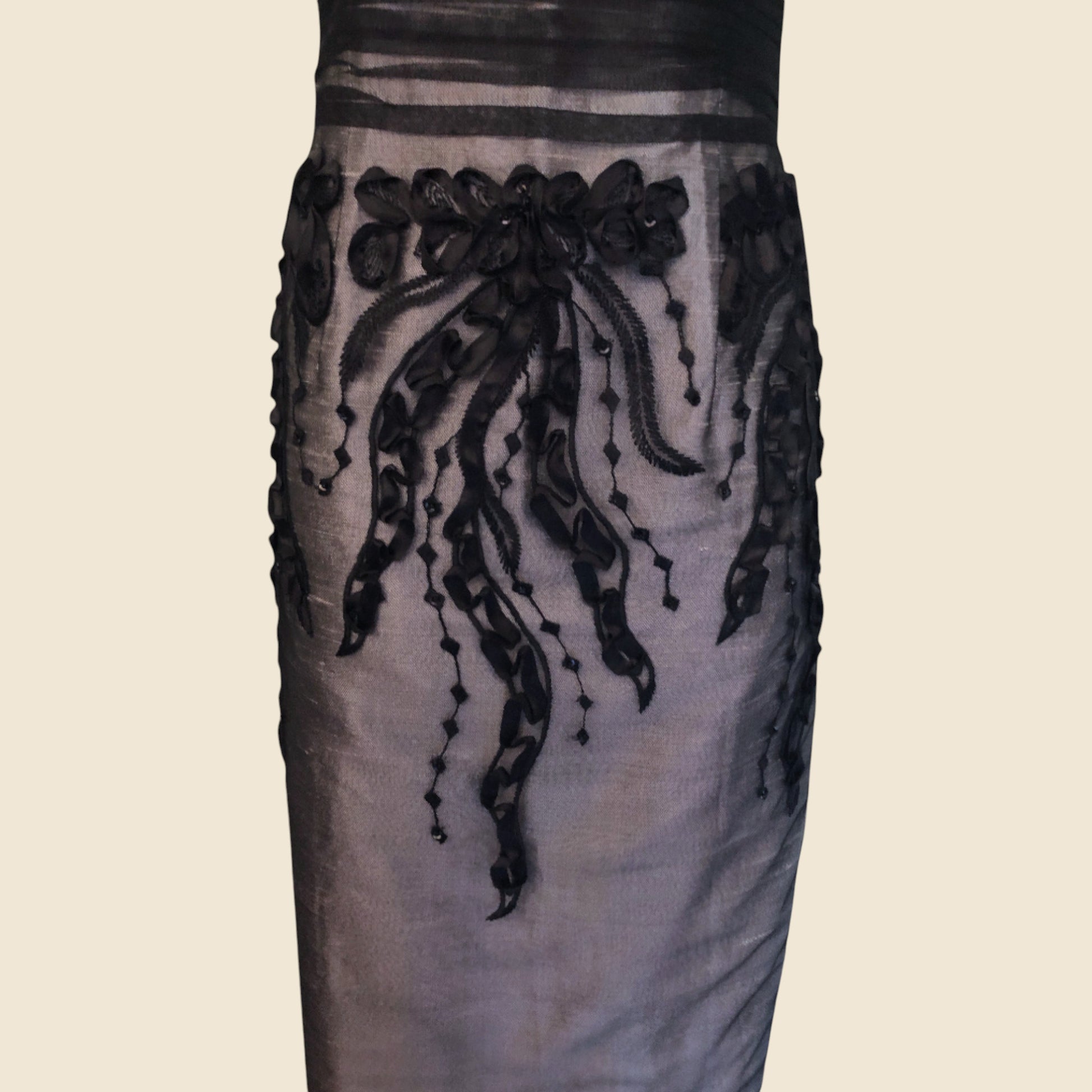 Dress with black floral embroidery on a beige background