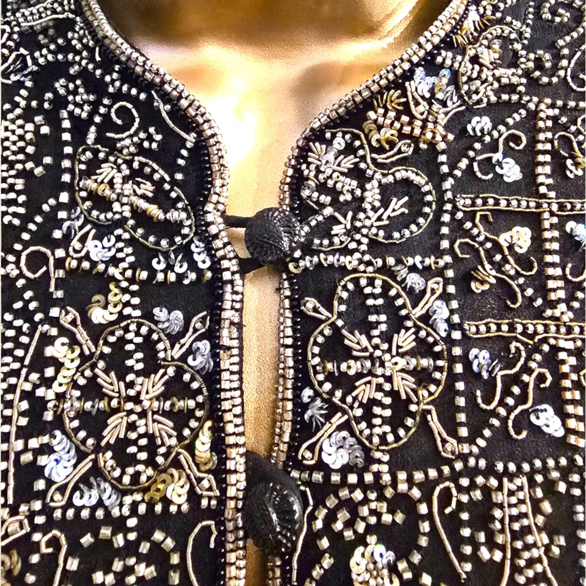 Close-up of a black garment with intricate gold embroidery on a blurred background