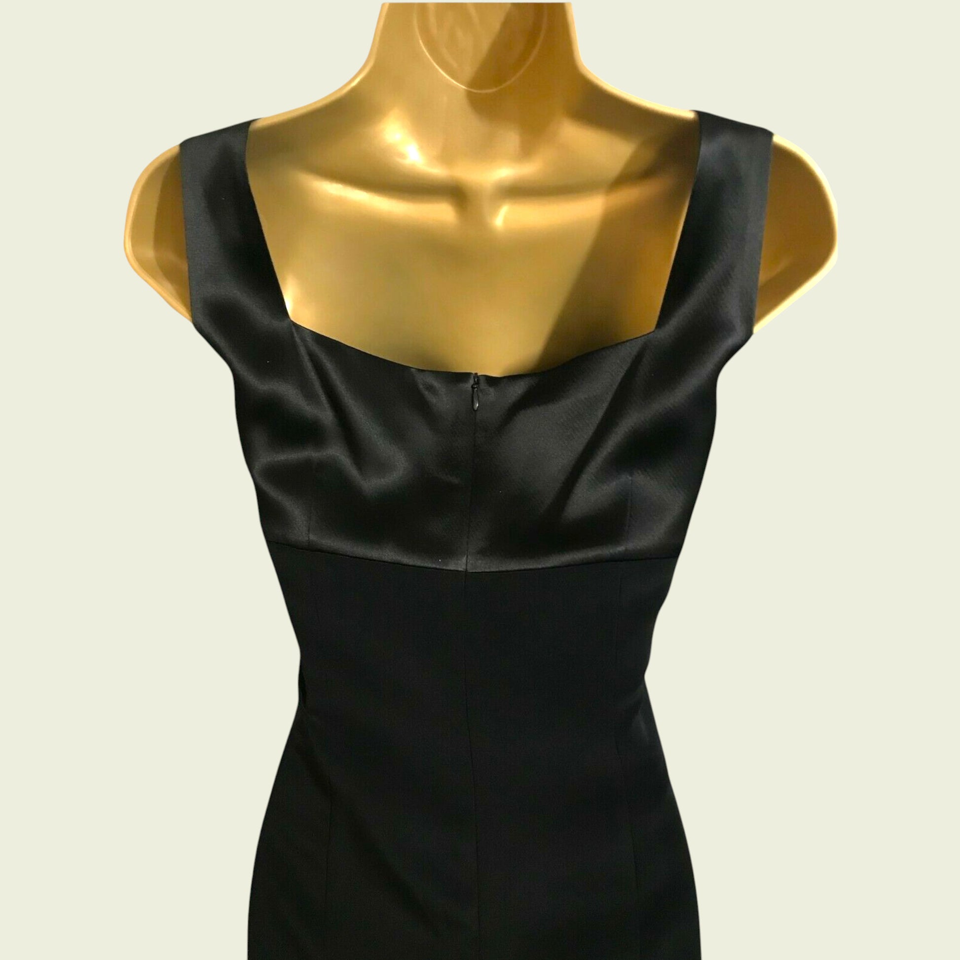 Black dress on a gold mannequin against a beige background