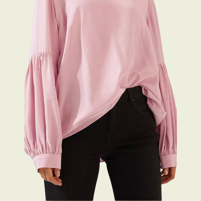 Pink blouse with balloon sleeves worn by a person on a beige background