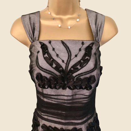 Gray sleeveless top with black floral embroidery on a mannequin against a beige background