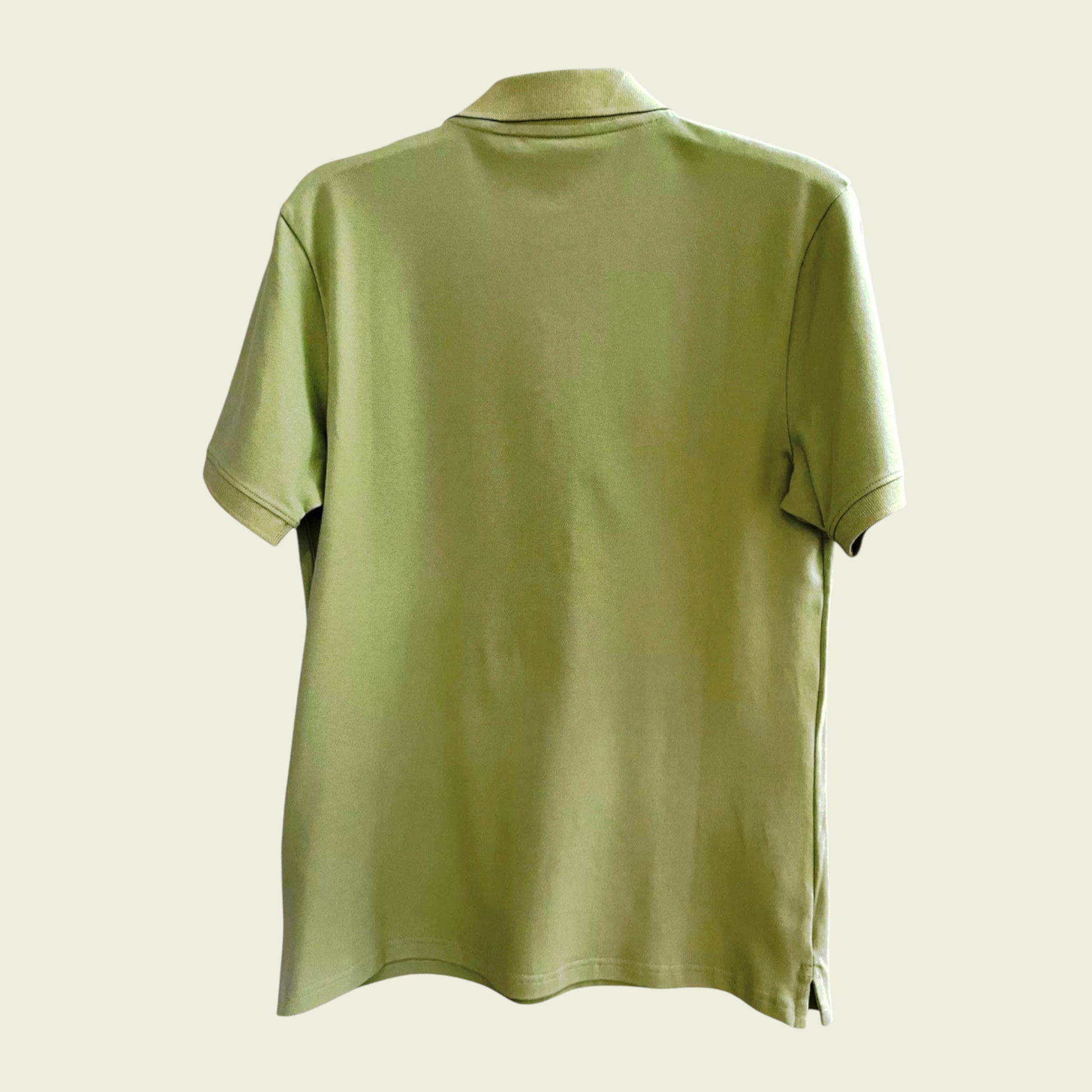 Green polo shirt on a beige background