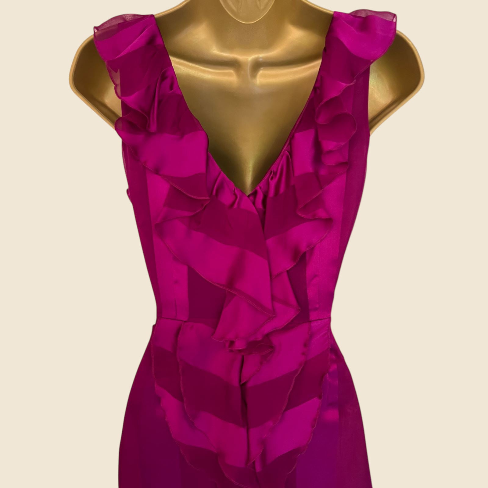 Fuchsia dress on a gold mannequin against a beige background