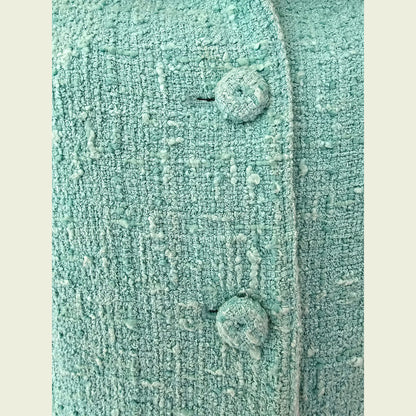Close-up of a textured turquoise fabric with buttons on a beige background