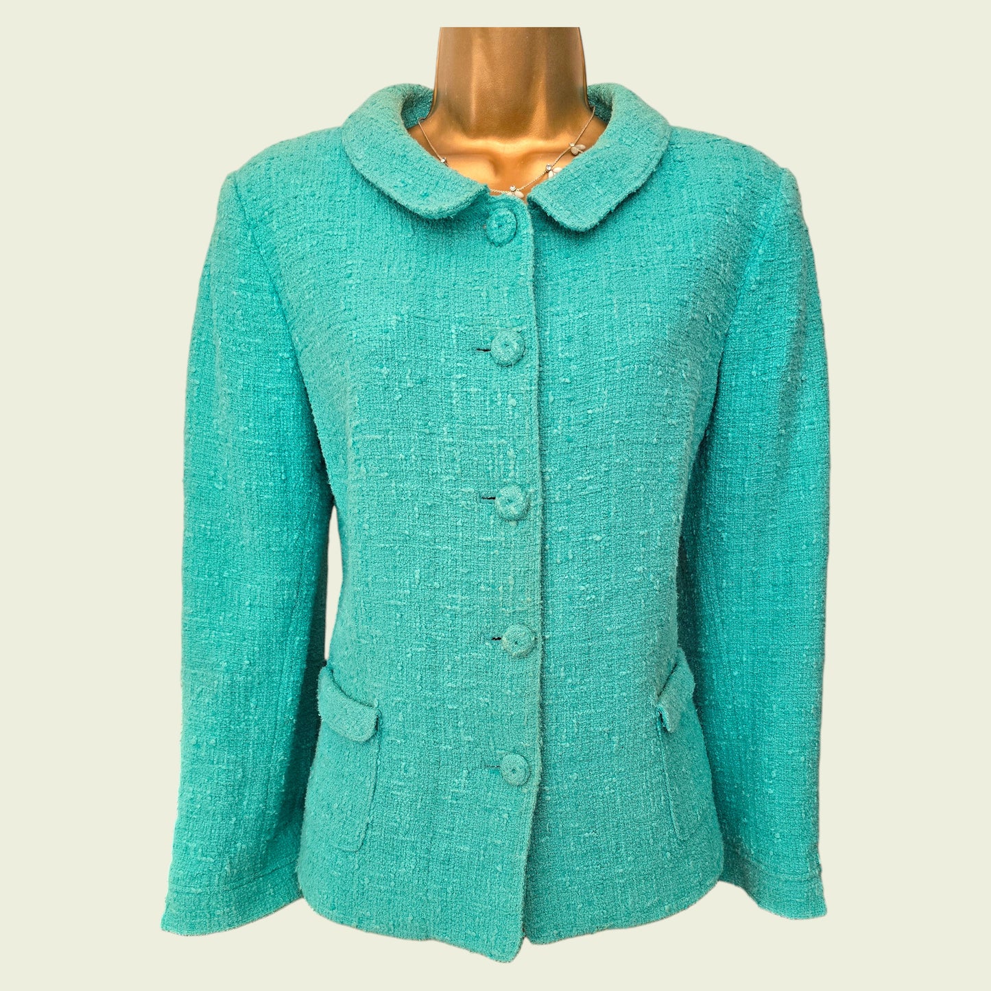 Turquoise jacket on a mannequin against a beige background