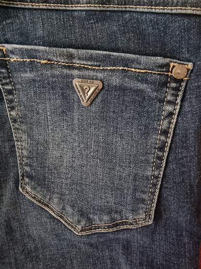Close-up of a blue denim pocket with a brand logo on a dark background