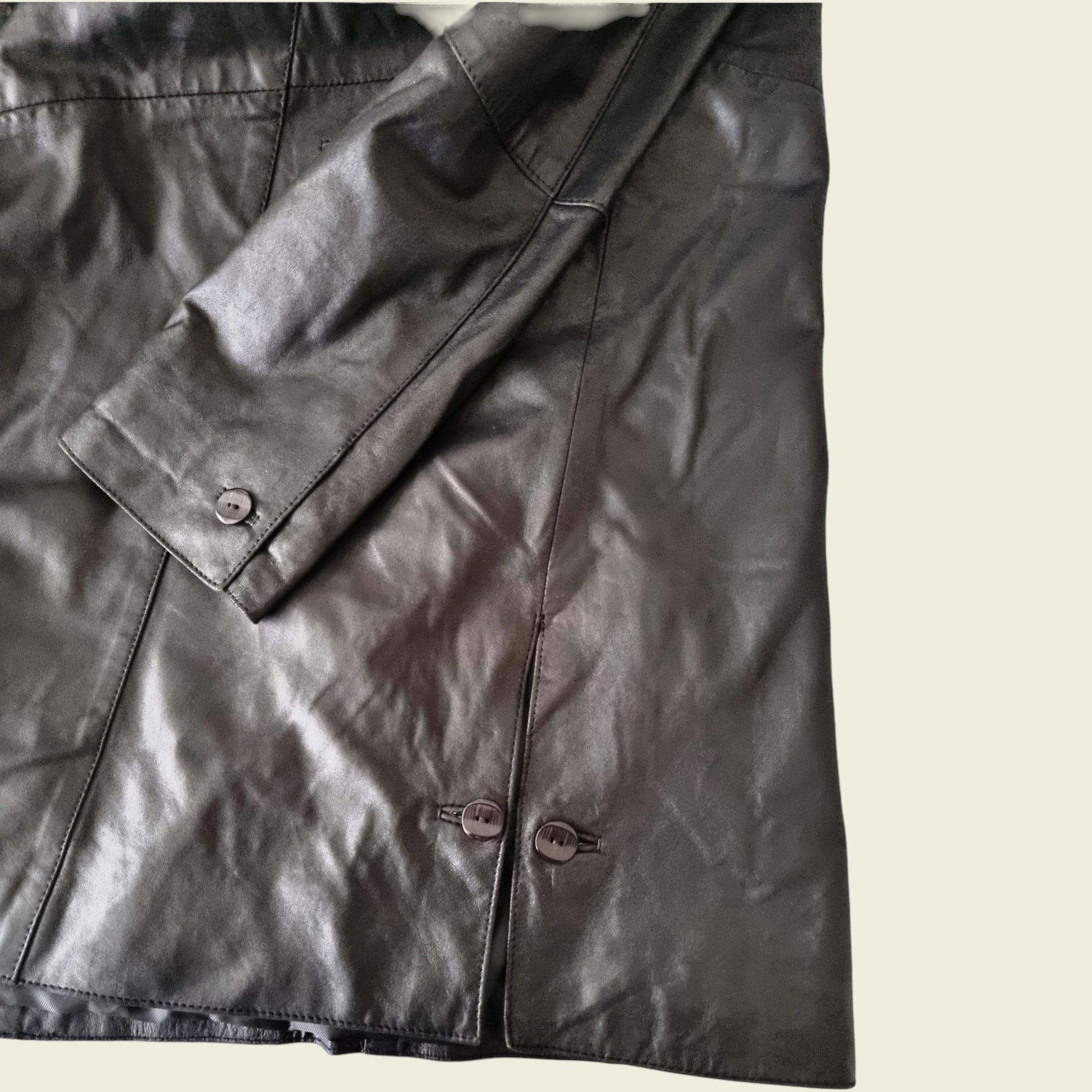 Close-up of a black leather jacket with buttons on a light background