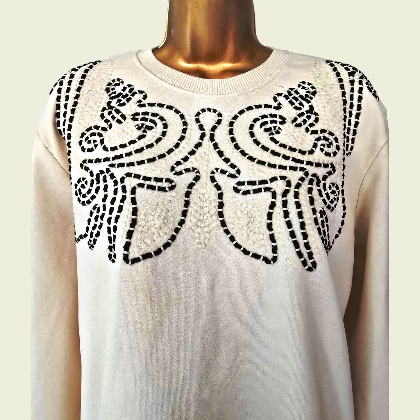 Beige sweater with brown floral pattern on a mannequin against a white background