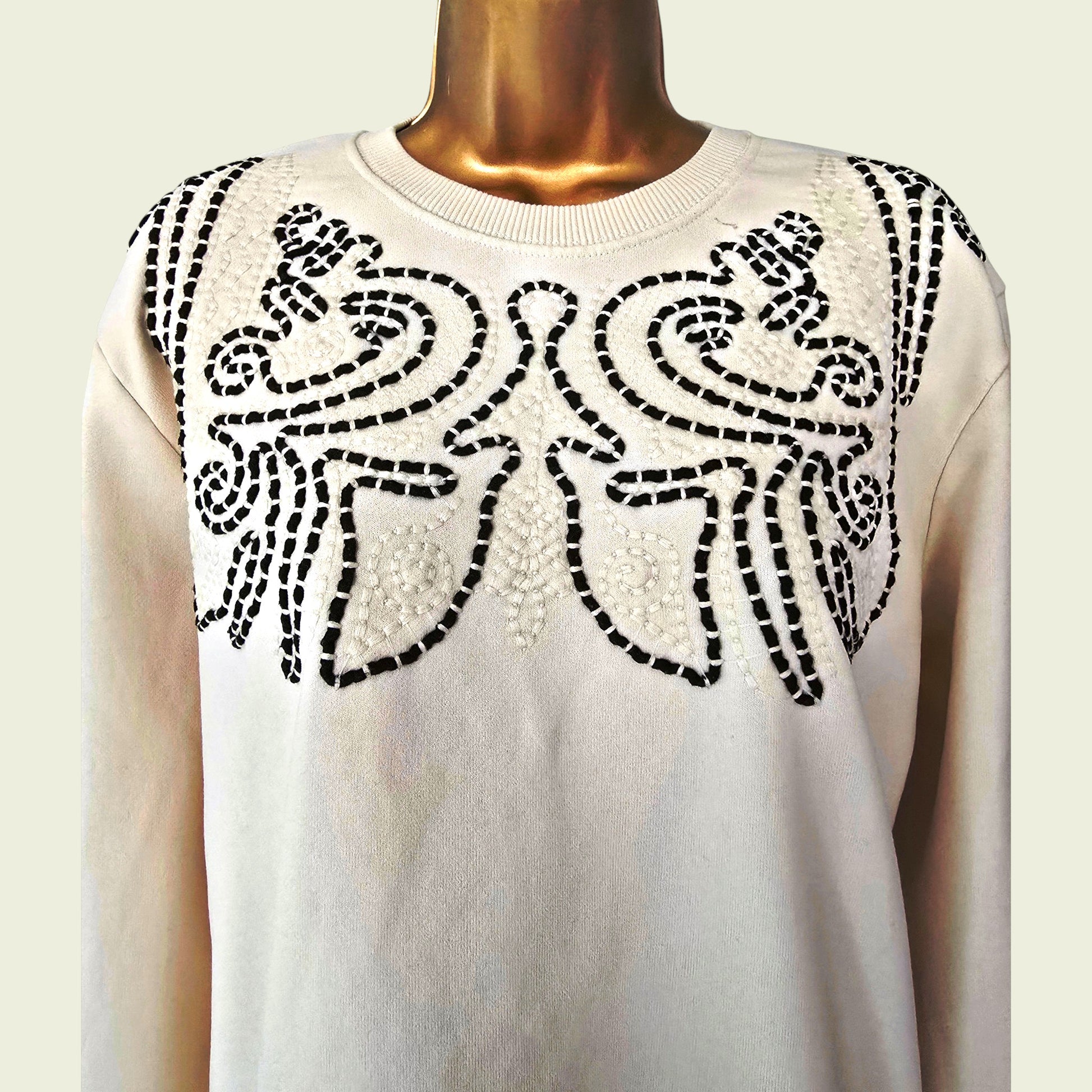 Beige sweater with brown floral pattern on a mannequin against a white background