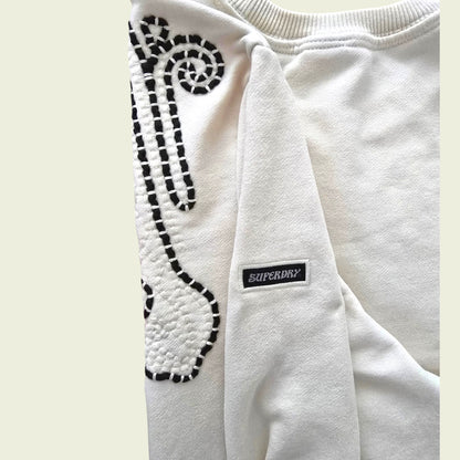 Beige sweatshirt with brown pattern and Superdry logo on a light beige background