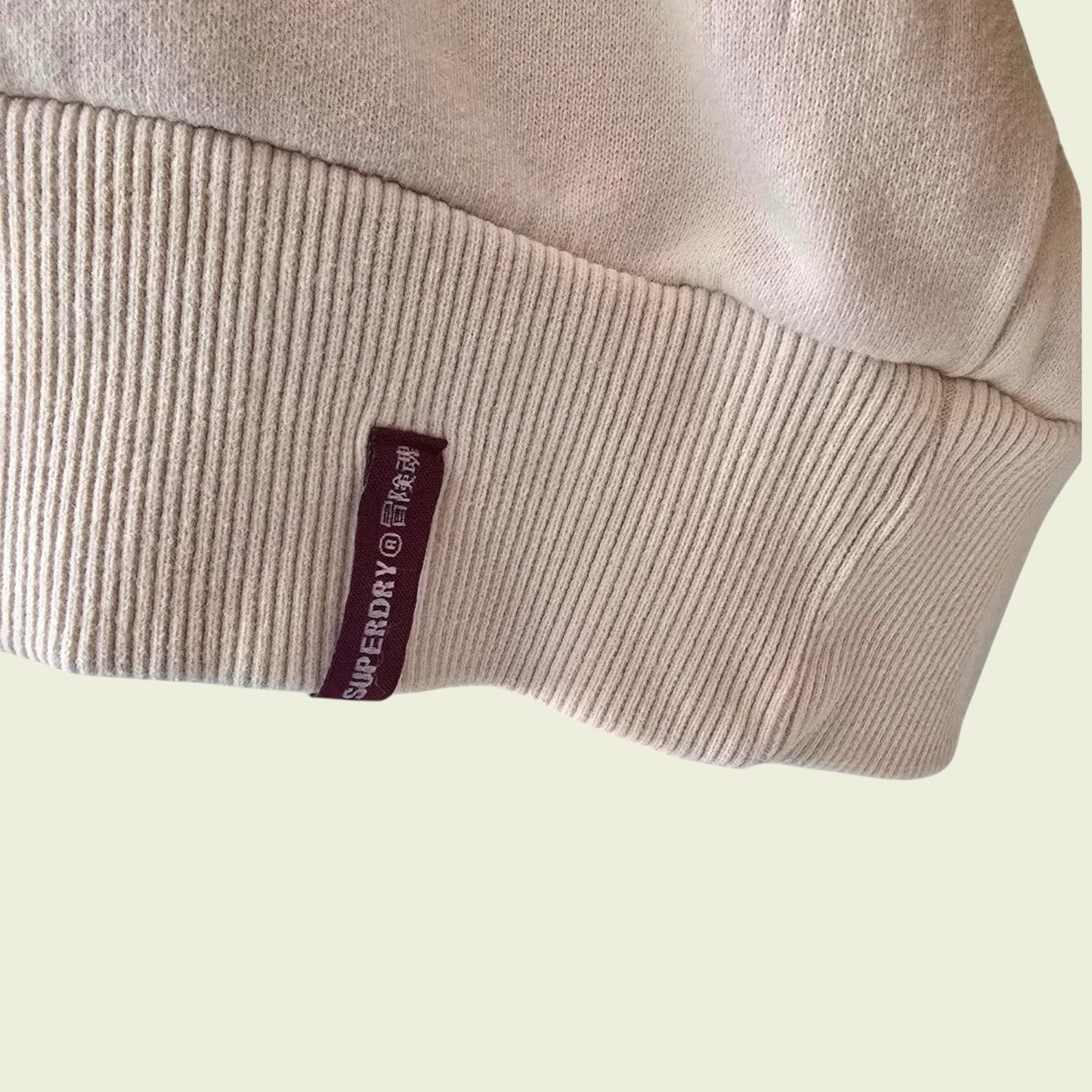 Superdry logo on a beige garment against a light background