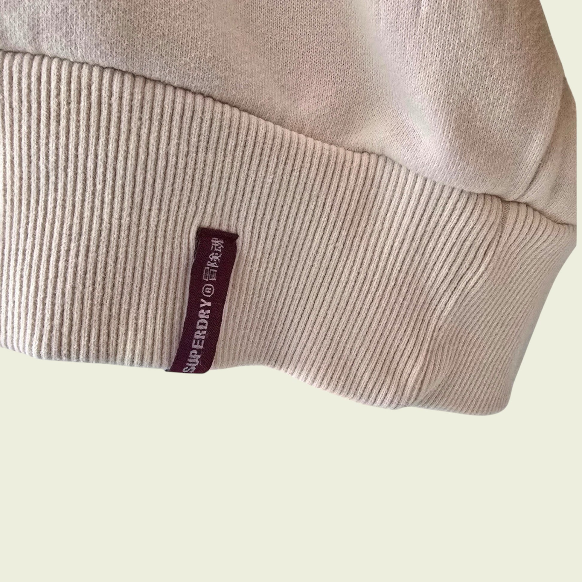 Superdry logo on a beige garment against a light background