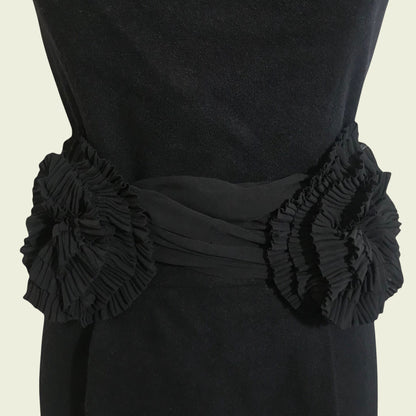 Black dress with floral embellishments on a beige background