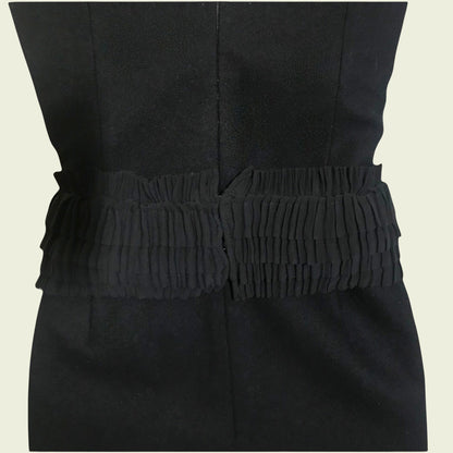 Black dress with a textured belt on a beige background