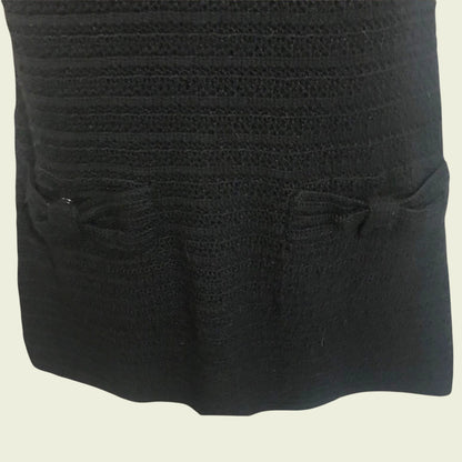 Close-up of a textured black fabric with two small bows on a beige background