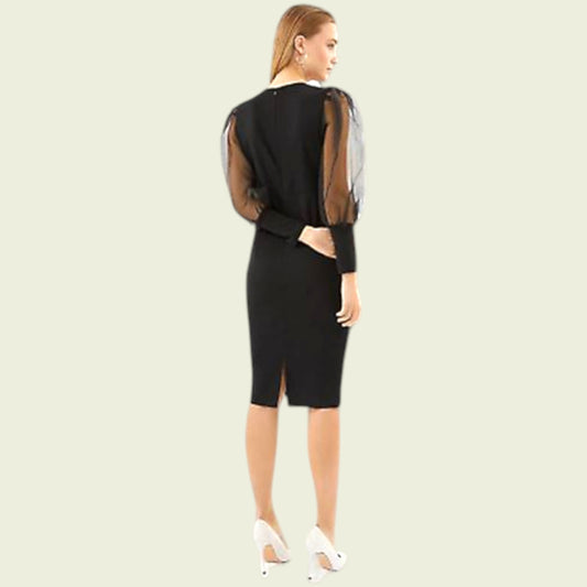 Woman wearing a black dress with sheer sleeves on a beige background